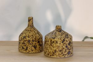 Small bottle forms, made from clay and ash glazed with a spotted and textured surface like reptile skin.